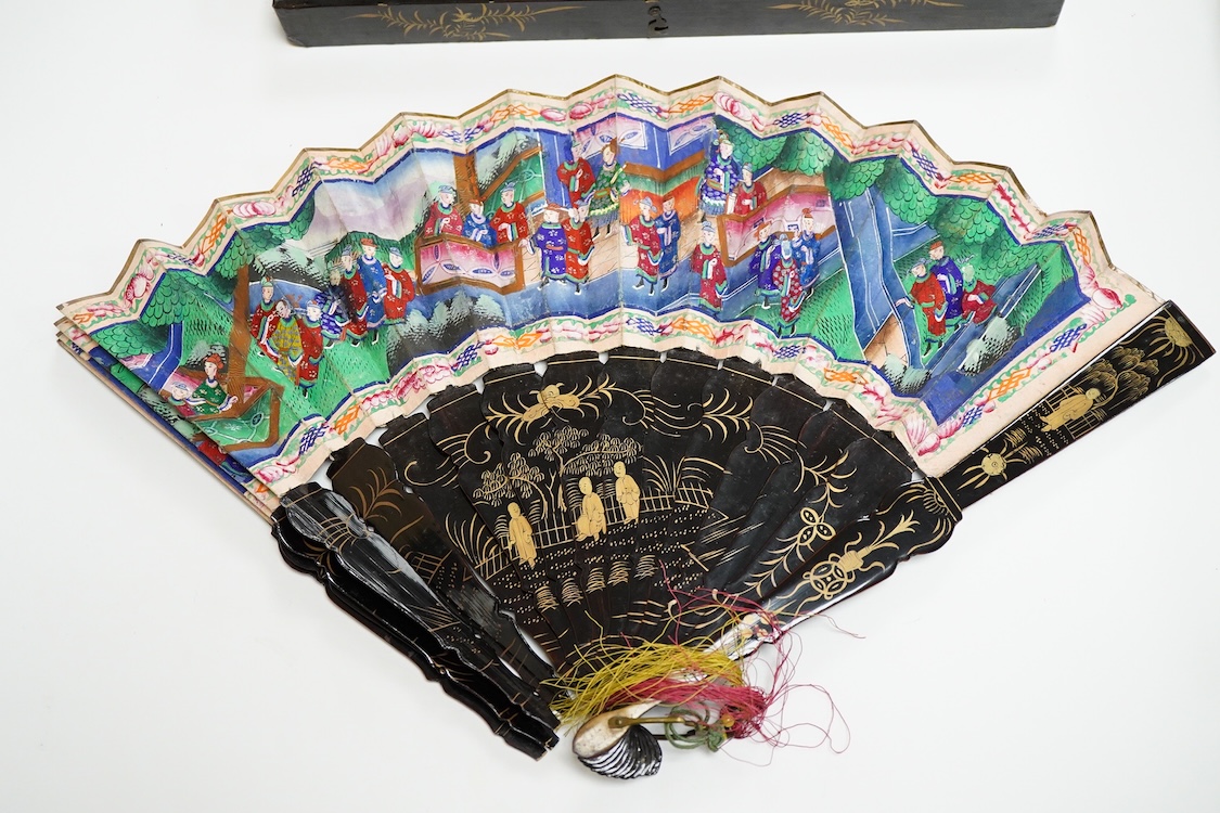 Four 19th century Chinese gilt-decorated black lacquer fans with figure painted leaves, two cased, largest 41cm